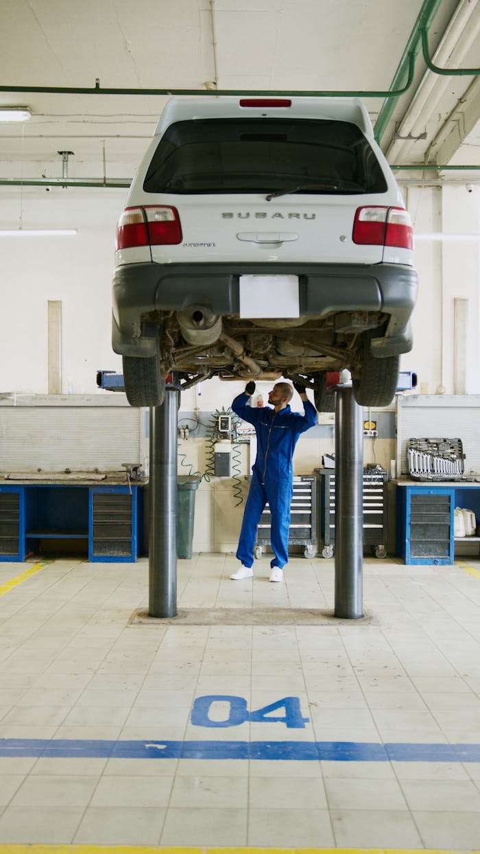 A professional mechanic checks a car on a lift in an auto repair shop.